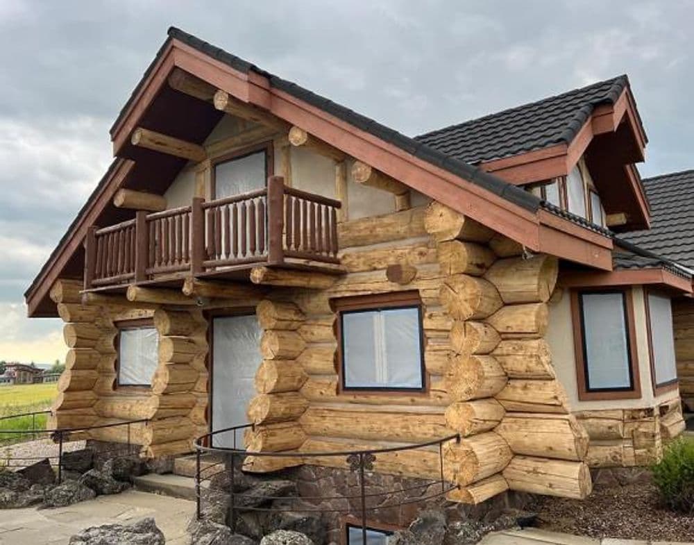 log cabin house with balcony and large windows, rustic architecture, surrounded by green fields