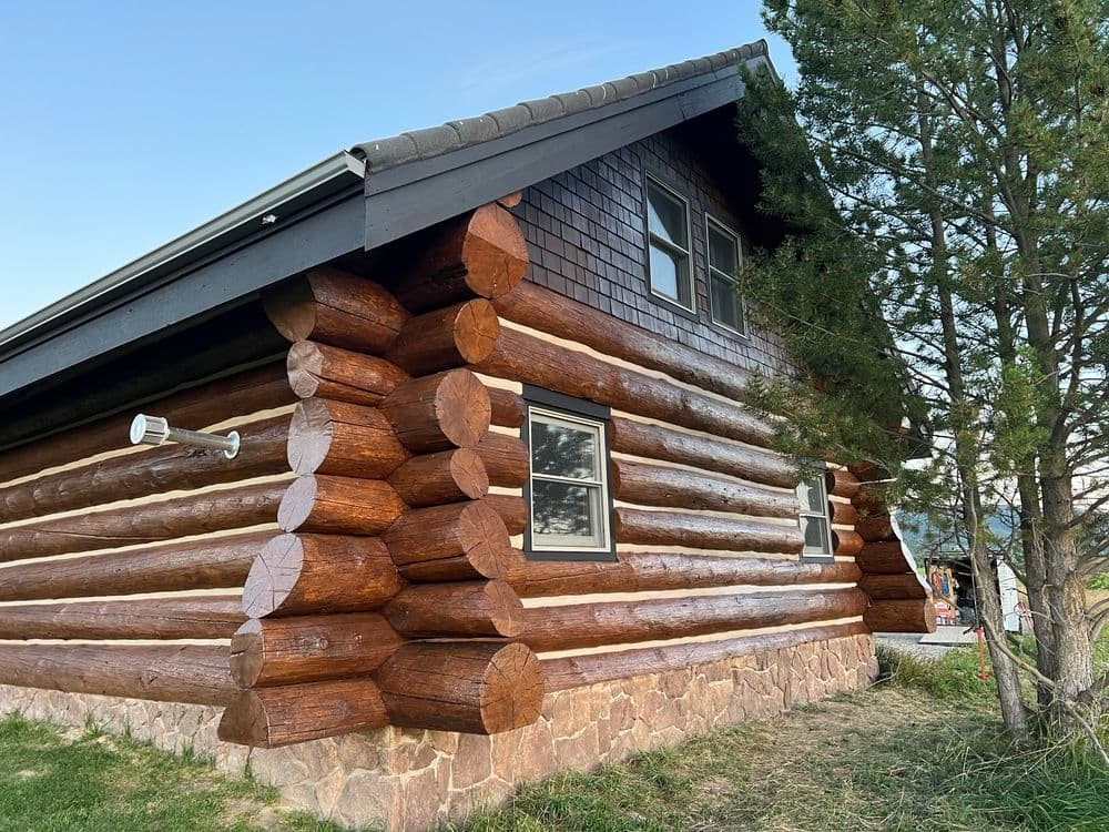 Log cabin exterior showcasing detailed wooden logs and a sloped roof against a clear sky.