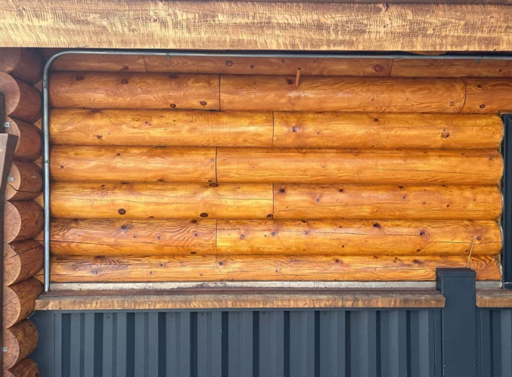 Log cabin wall with rich wood texture and metal accents, showcasing rustic architecture.