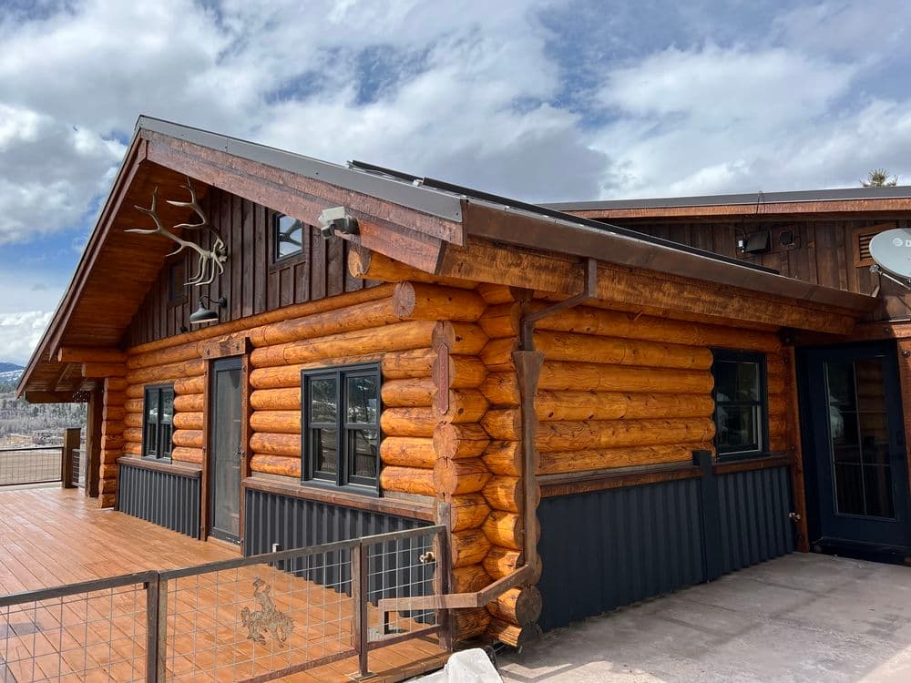Log cabin exterior with wooden logs and metal accents against a dramatic sky.