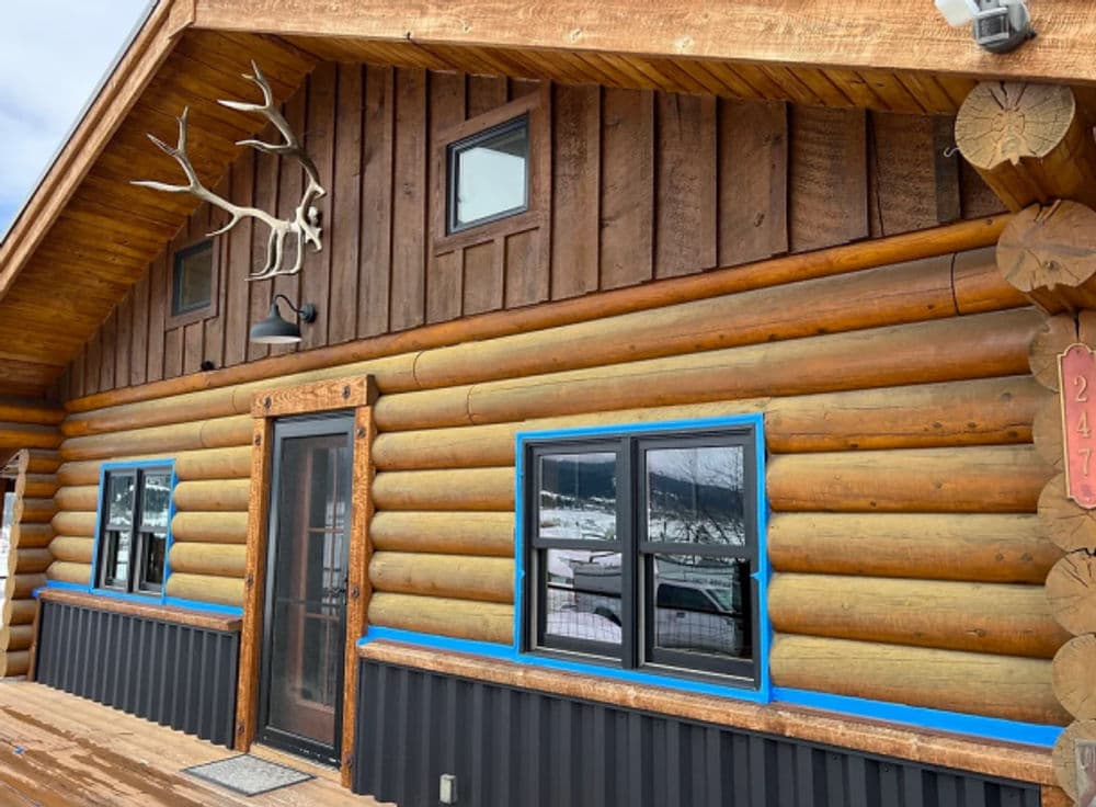 Log cabin exterior with large windows, wooden accents, and a decorative antler sculpture.